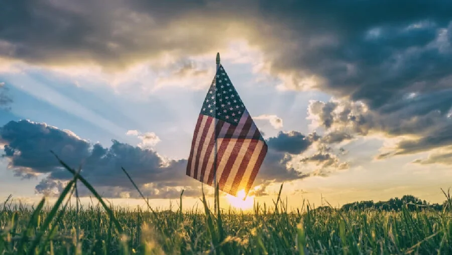 Gün batımında çayıra dikilmiş Amerikan bayrağı — ABD vergi ve ödeme sistemleri