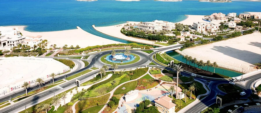 A waterfront promenade, palm trees and modern towers in Qatar.